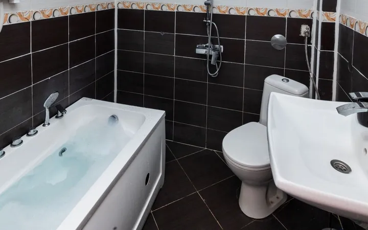 Bathroom with a bathtub, black tiles and a shower