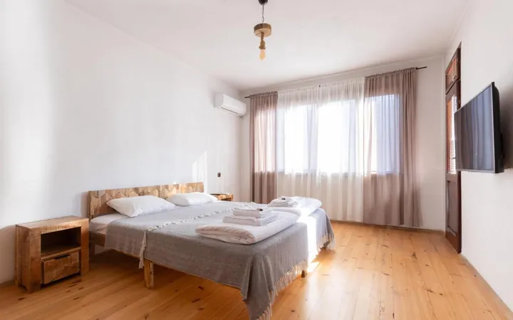 Bright double bedroom with wooden floor and wall-mounted TV
